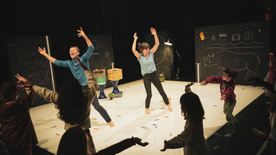 Deux danseurs dansent et rient entourés d'enfants.