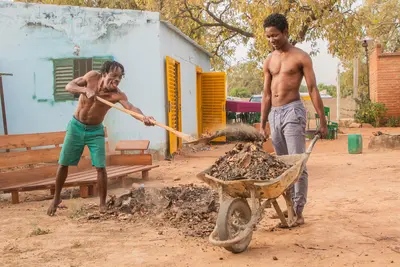 Deux hommes travaillant. L'un portant une brouette, l'autre la remplissant de débris.