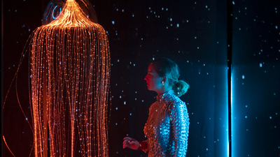 Une femme en tenue de plongée, à côté d'une méduse lumineuse.
