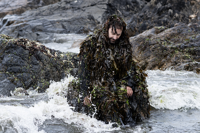 Un homme recouvert d'algues dans la mer.