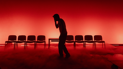 Un homme seul se promène dans la pénombre, la lumière est rouge.