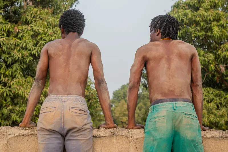 Deux hommes torse-nu sur un mur, de dos.